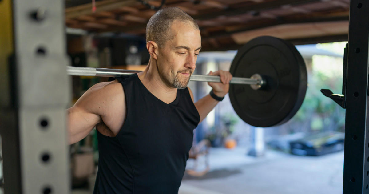 Man doing barbell squat in a gym